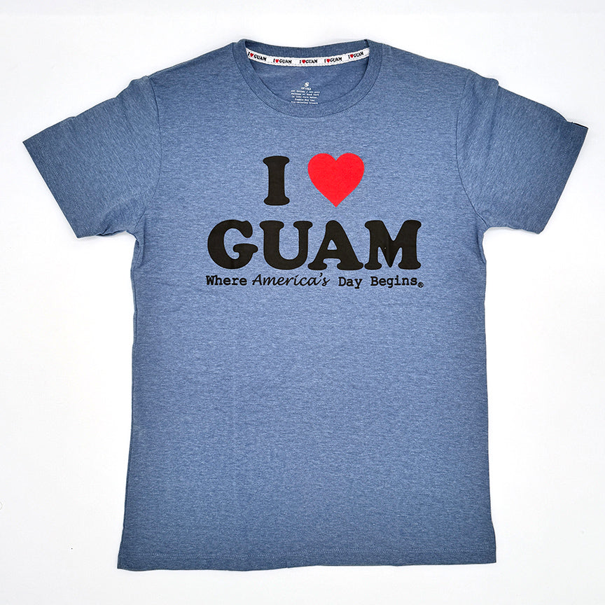 Baby blue unisex t-shirt with ‘I ❤️ GUAM’ in bold yellow letters and a red heart, accompanied by the slogan ‘Where America’s Day Begins’ in yellow text. The design celebrates Guam’s identity and unique time zone.